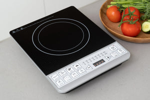 Induction Cooker on a kitchen benchtop next to a bowl of veggies.