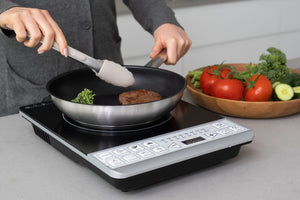 Woman cooking a steak on a frying pan on the single Induction Cooker.