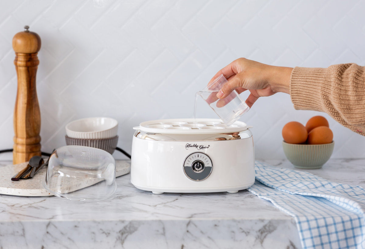 Pouring water into the Electric Egg Steamer using the included measuring cup.
