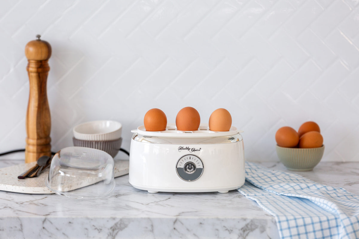 Eggs sitting in the Electric Egg Steamer and the lid is next to the appliance.