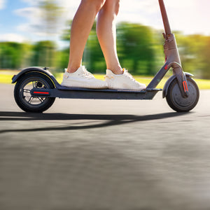 A person riding the ES60 Electric Scooter in a park.