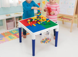 Children playing with colorful building blocks on a multi-colored table in a playroom setting.