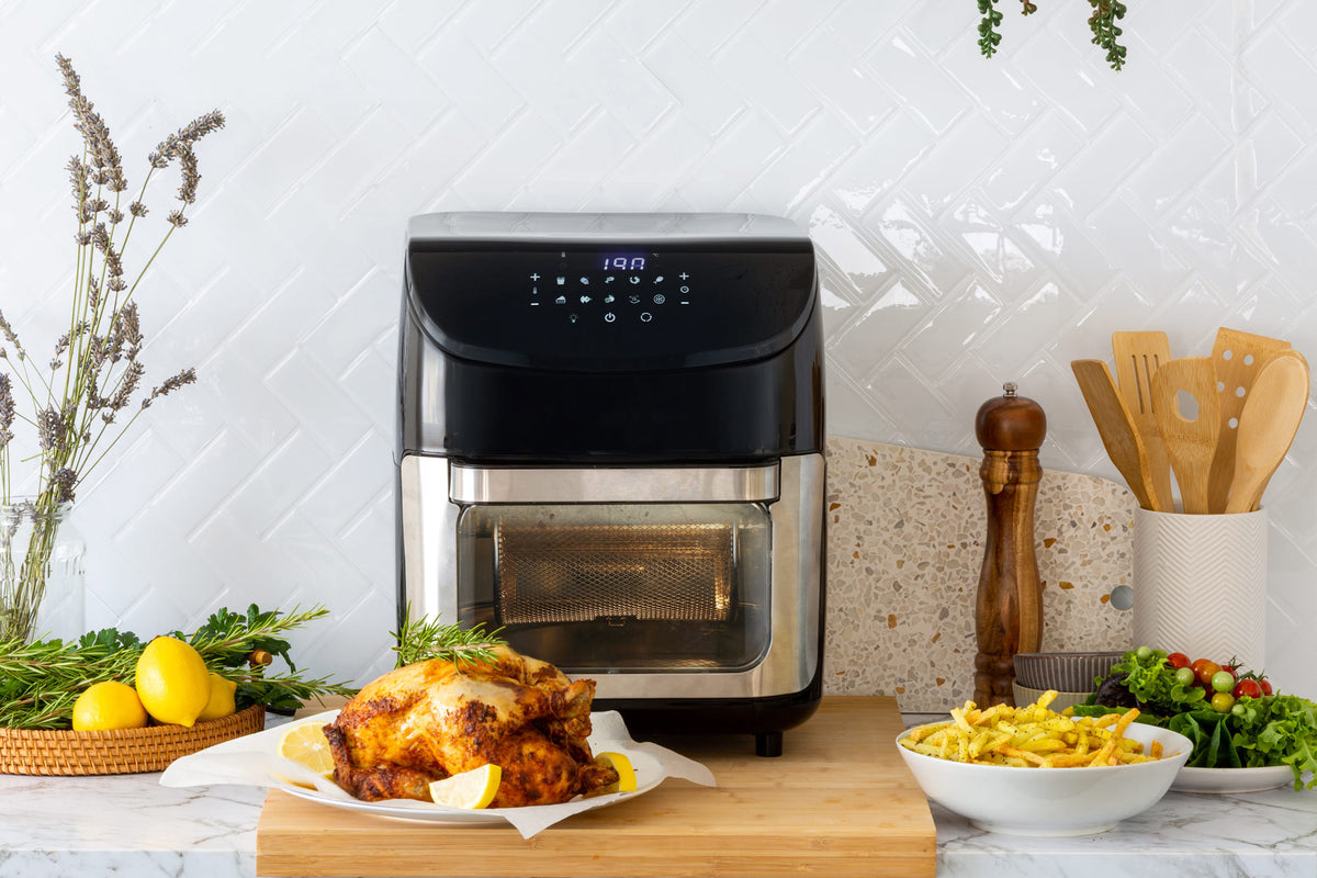 12L Digital Air Fryer Oven in a modern kitchen with freshly cooked chicken and a bowl of hot chips in front of it.