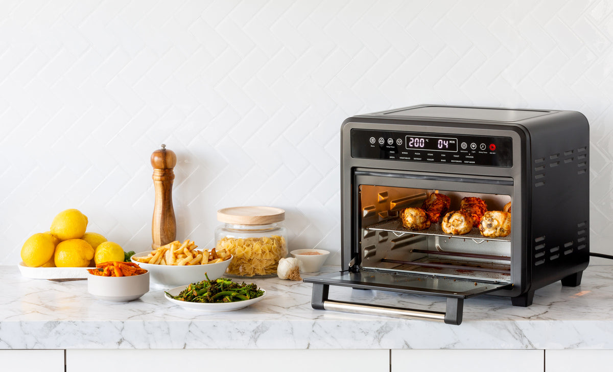 23L Digital Air Fryer Convection Oven in a modern kitchen cooking chicken drumsticks.