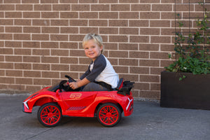 Child driving the BZL909 red electric car ride on in a driveway.