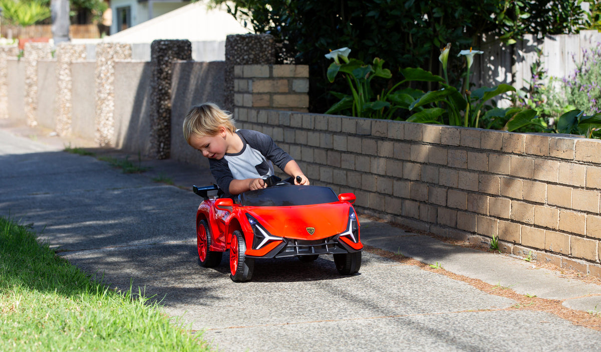 Child driving the BZL909 red electric car ride on along a footpath.