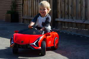BZL909 red electric car ride on being used in a driveway by a happy child.