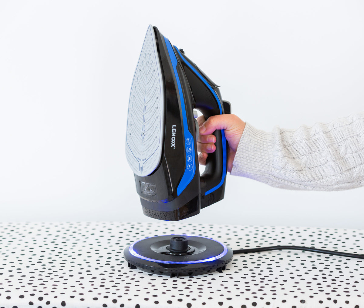 Woman picking up the cordless steam iron from the 360° charging base.