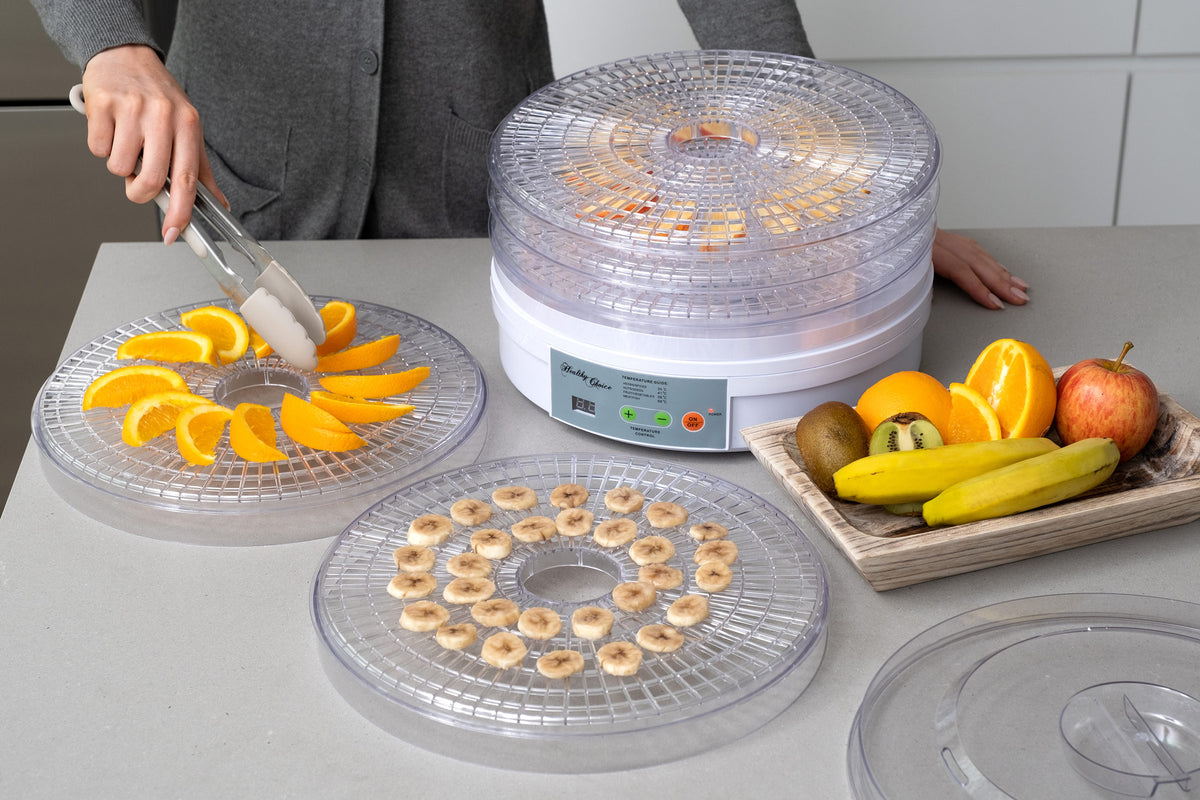 Tray of oranges and bananas next to the round food dehydrator.