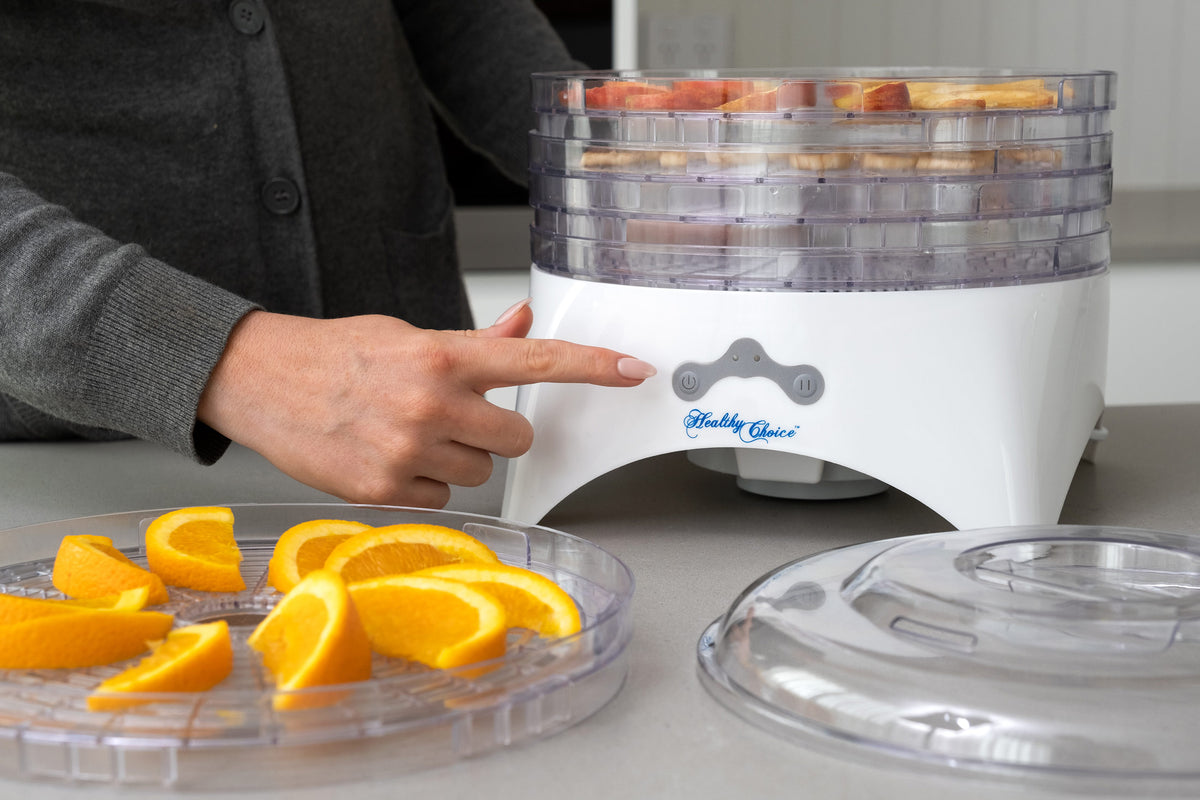 Woman preparing oranges and apples for dehydrating.