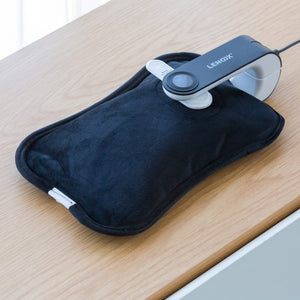 Rechargeable Electric Hot Water Bottle with the charger connected on a wooden table.
