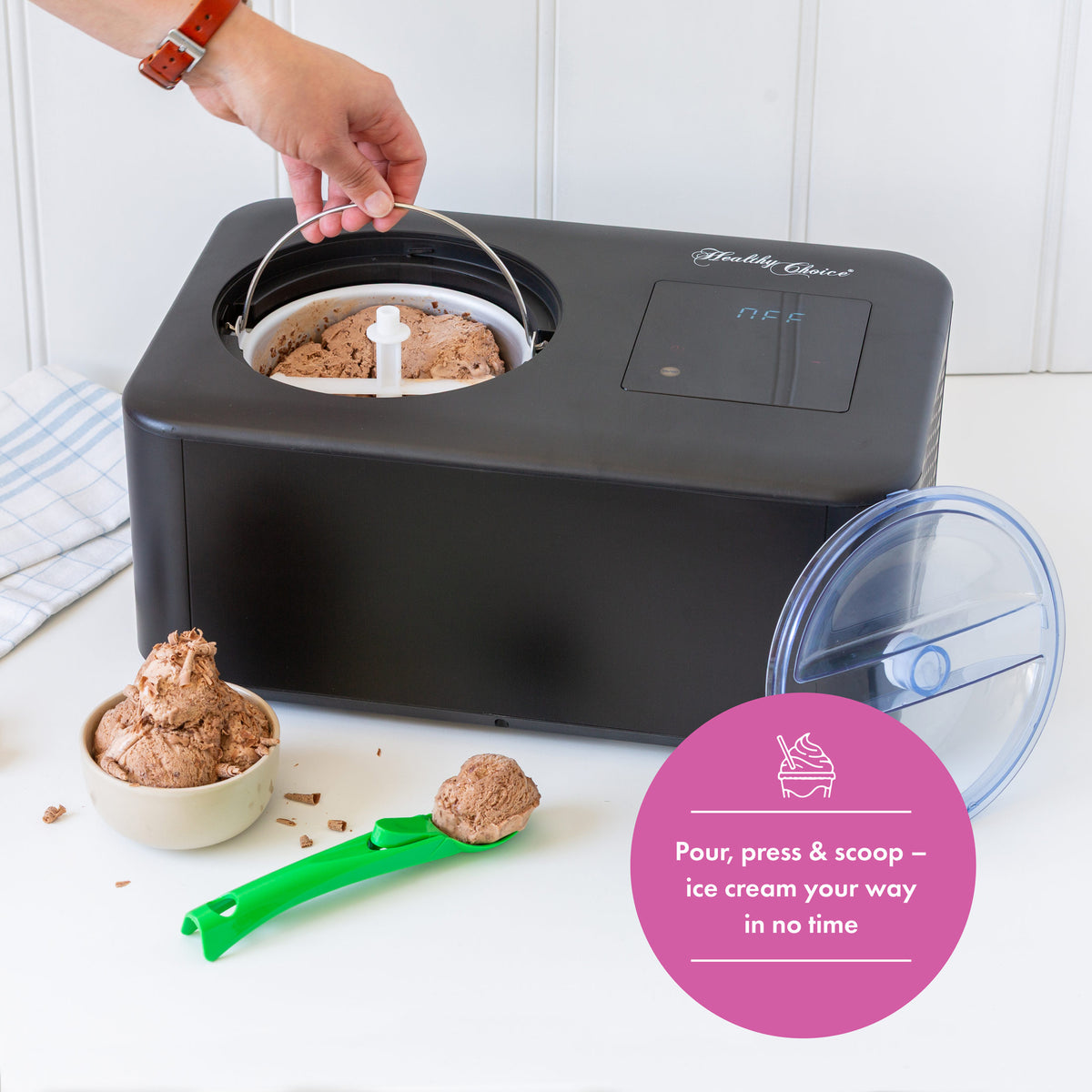 Black ice cream maker with chocolate ice cream and a scoop on a white surface.