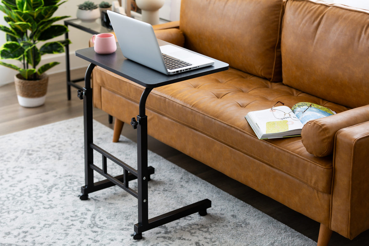 Black Portable Laptop Desk with Adjustable Height in front of a modern sofa, set up for laptop work.