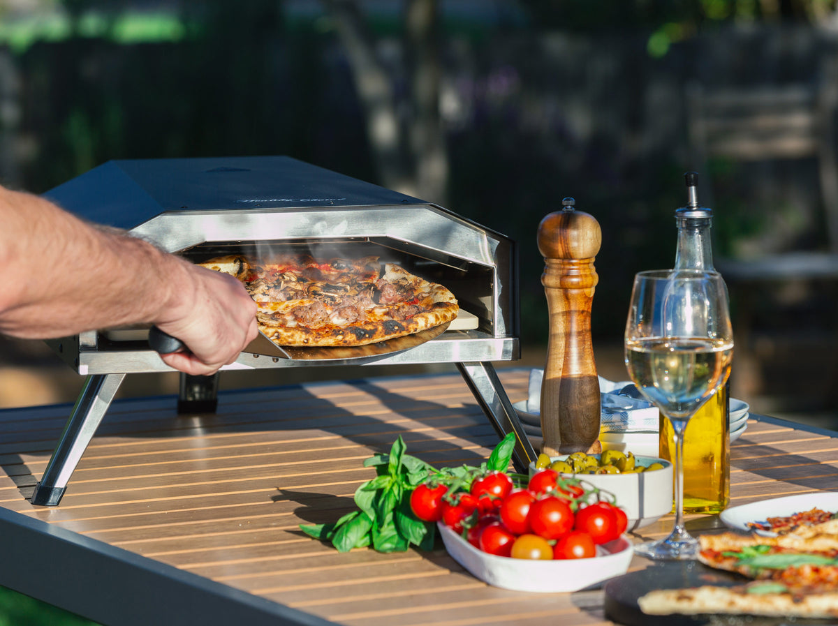 Man taking a piping hot pizza out of the Healthy Choice 13" Gas Pizza Oven
