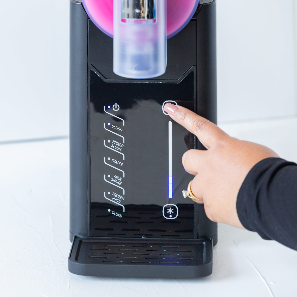 Hand pressing a button on the slushie maker against a white background