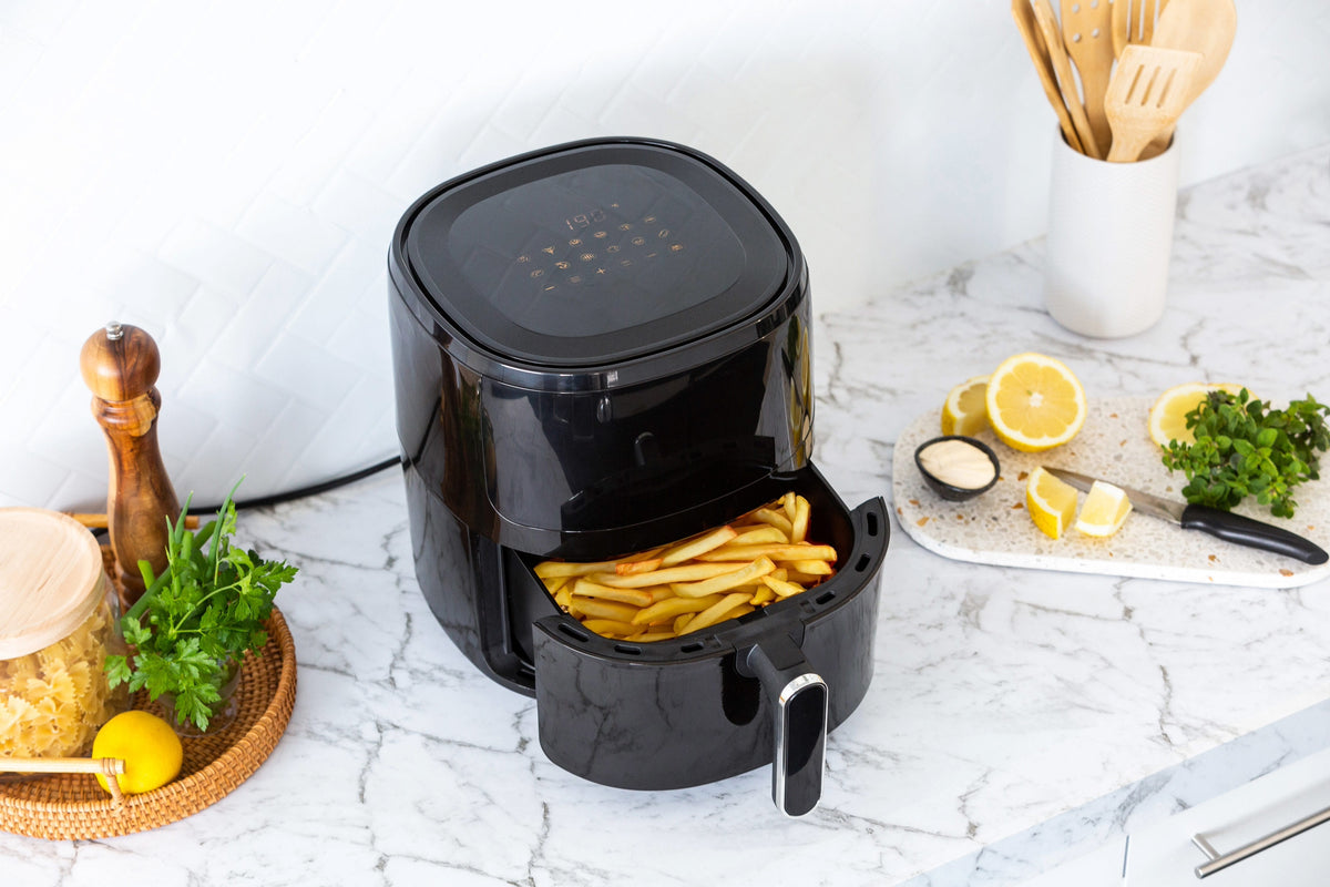  6L Digital Air Fryer AF605 filled with golden fries that just finished cooking in a modern bright kitchen.