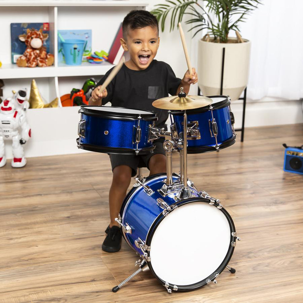 Happy child playing the drums in a playroom.