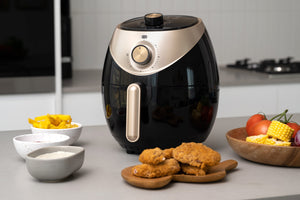 AF350 3.5L Air Fryer on a kitchen bench with air fried food displayed on plates around it.