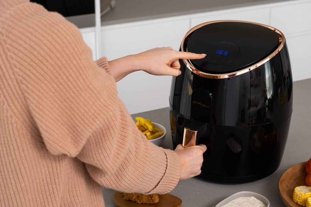 AF720 Air Fryer on a kitchen banchtop. Woman's hand hovering over the digital screen, changing the temperature setting.