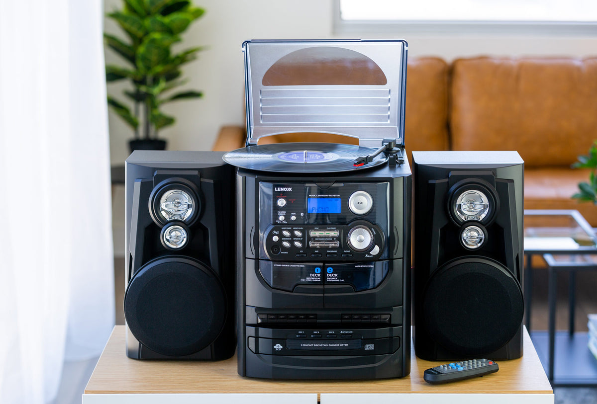 CD7400N with the vinyl recod player on top open, set on a table in a living room.