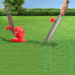 Red & grey cricket ball pitcher being used in a backyard setting.